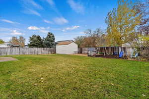 View of yard featuring a playground and a storage shed