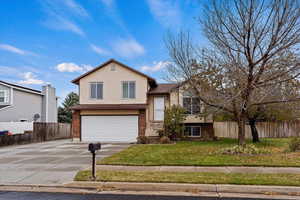 Tri-level home featuring a garage and a front yard