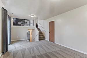 Unfurnished living room with a textured ceiling and carpet flooring