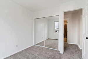 Unfurnished bedroom featuring light carpet and a closet