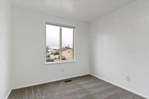 Carpeted empty room featuring a textured ceiling