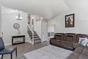 Living room featuring hardwood / wood-style floors, vaulted ceiling, and a notable chandelier