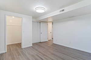 Basement with light hardwood / wood-style floors and a textured ceiling