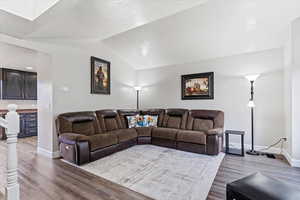 Living room with hardwood / wood-style floors, a textured ceiling, and vaulted ceiling