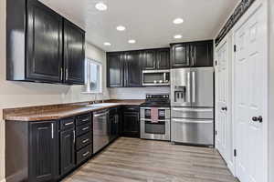 Kitchen with a textured ceiling, light hardwood / wood-style floors, stainless steel appliances, and sink