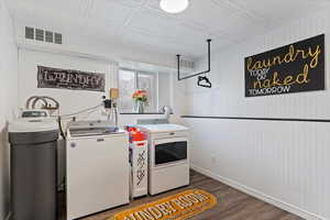 Washroom with wood walls, hardwood / wood-style flooring, and independent washer and dryer