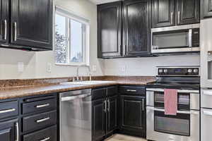 Kitchen with appliances with stainless steel finishes, sink, and light hardwood / wood-style flooring