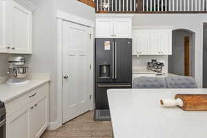 Kitchen with stainless steel refrigerator with ice dispenser, light wood-type flooring, and white cabinetry