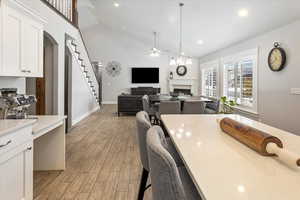 Dining space featuring ceiling fan, light wood-type flooring, and high vaulted ceiling