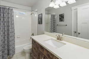 Full bathroom with tile patterned flooring, vanity, shower / tub combo with curtain, and toilet