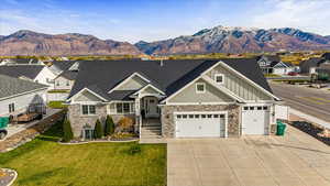 View of front of property with a mountain view, central air condition unit, a garage, and a front yard