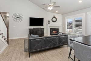 Living room featuring ceiling fan, high vaulted ceiling, and light wood-type flooring