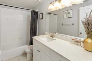 Full bathroom with tile patterned flooring, vanity, shower / tub combo with curtain, and toilet