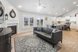 Living room featuring light hardwood / wood-style flooring, high vaulted ceiling, ceiling fan with notable chandelier, and sink