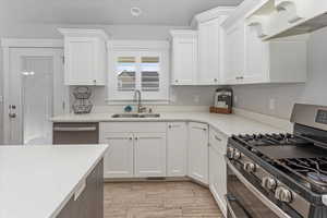 Kitchen featuring white cabinetry, sink, stainless steel appliances, and light hardwood / wood-style floors