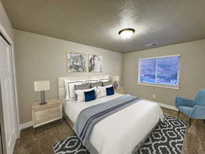 Bedroom with dark carpet and a textured ceiling