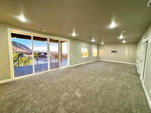 Unfurnished room featuring carpet flooring, a mountain view, and a textured ceiling