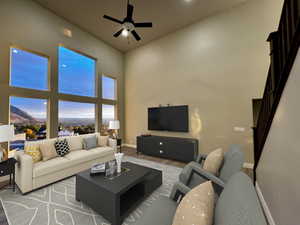 Living room with hardwood / wood-style floors, a towering ceiling, and ceiling fan