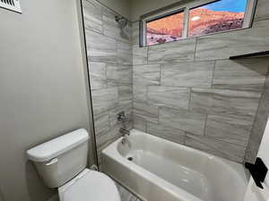 Bathroom featuring tiled shower / bath combo and toilet