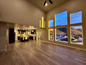 Unfurnished living room featuring a mountain view, a towering ceiling, and wood-type flooring