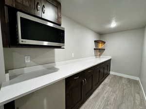 Kitchen featuring dark brown cabinets and light wood-type flooring