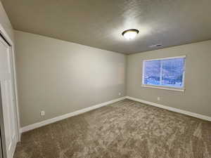 Empty room featuring carpet and a textured ceiling