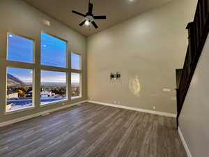 Unfurnished room featuring a high ceiling, dark hardwood / wood-style floors, and ceiling fan