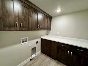 Laundry area featuring cabinets, hookup for a washing machine, light hardwood / wood-style flooring, and hookup for an electric dryer