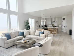 Living area featuring light wood-type flooring, plenty of natural light, a towering ceiling, and an inviting chandelier