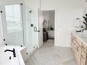 Full bath featuring a sink, baseboards, a shower stall, a tub, and double vanity