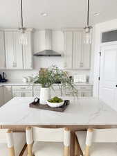 Kitchen featuring hanging light fixtures, wall chimney exhaust hood, and a kitchen island