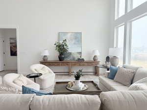 Living area with a towering ceiling, baseboards, and wood finished floors