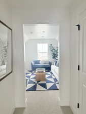 Living room with vaulted ceiling, a textured ceiling, baseboards, and light colored carpet