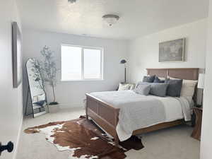 Bedroom with light carpet, visible vents, baseboards, and a textured ceiling