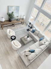 Living area with a healthy amount of sunlight, light wood-style floors, and a high ceiling