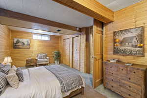 Bedroom with beamed ceiling, carpet floors, and wooden walls (Staged by AI)