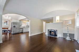 Living room with dark hardwood / wood-style flooring, a textured ceiling, sink, a notable chandelier, and lofted ceiling