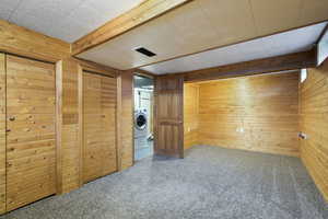 Basement featuring washer / dryer, carpet floors, and wood walls