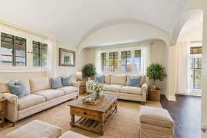 Living room with a textured ceiling, wood-type flooring, and lofted ceiling  (Staged by AI)