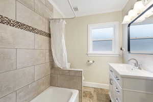 Full bathroom with vanity, toilet, crown molding, and shower / tub combo with curtain