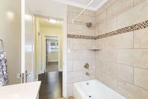 Bathroom with crown molding, tiled shower / bath, and hardwood / wood-style flooring