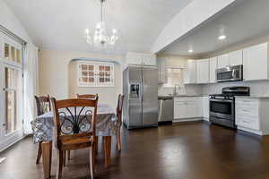 Kitchen featuring white cabinetry, dark wood-type flooring, stainless steel appliances, and lofted ceiling