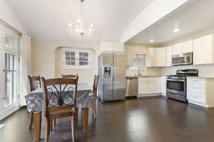 Kitchen featuring pendant lighting, stainless steel appliances, white cabinetry, and dark hardwood / wood-style floors