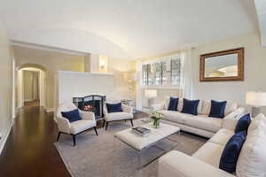 Living room featuring wood-type flooring, a textured ceiling, and vaulted ceiling  (Staged by AI)