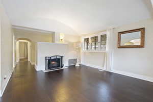 Unfurnished living room with dark hardwood / wood-style flooring, a textured ceiling, and vaulted ceiling