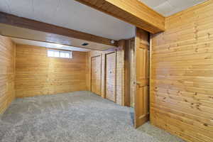 Bonus room featuring beamed ceiling, carpet floors, and wooden walls