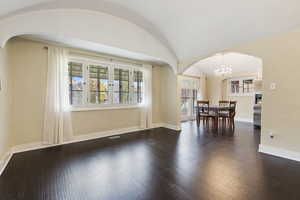 Unfurnished dining area with a chandelier, dark hardwood / wood-style floors, and lofted ceiling