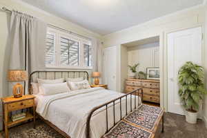 Carpeted bedroom with crown molding and a textured ceiling (Staged by AI)