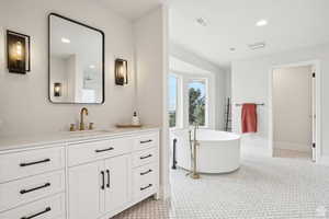 Bathroom featuring a washtub and vanity