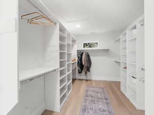 Walk in closet with hardwood / wood-style floors